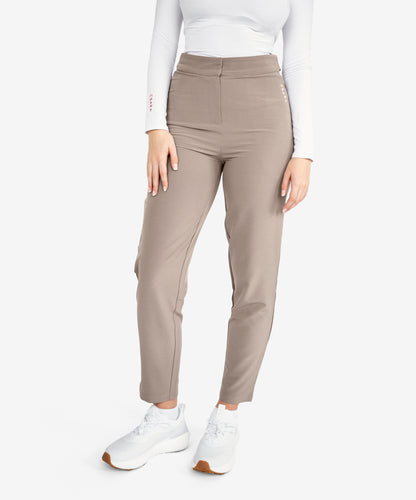 Model wearing mocha brown trousers with white trainers