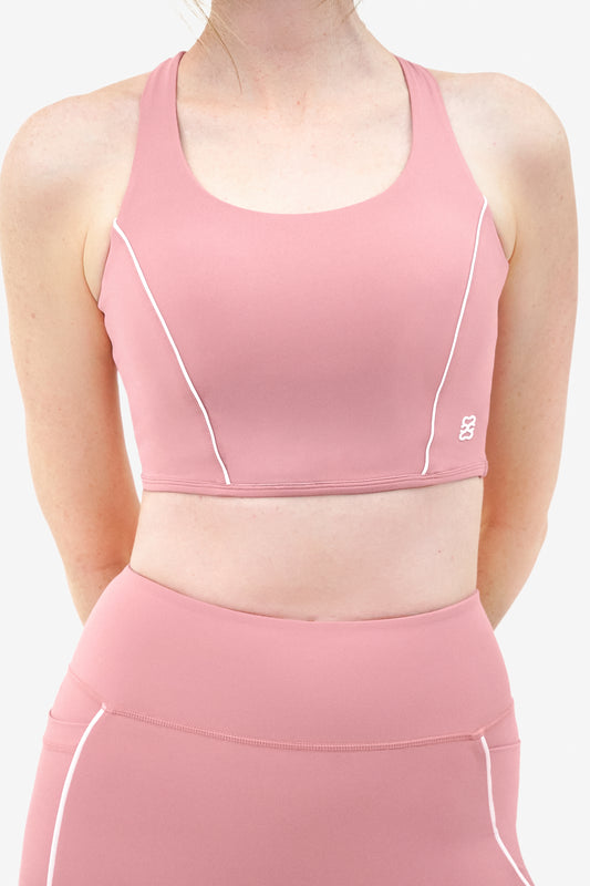 Pink long-line sports bra with white piping and adjustable straps, with white logo